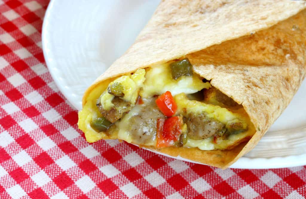 Close up of a plated breakfast burrito on a table with a red checkered tablecloth