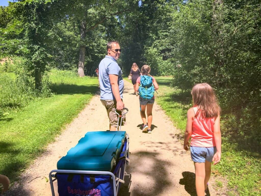 Girls walking to camp with their dad who is pulling a wagon
